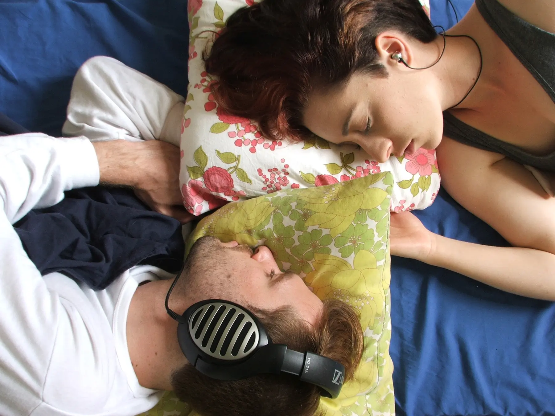 A man and a woman sleep with their heads on pillows
