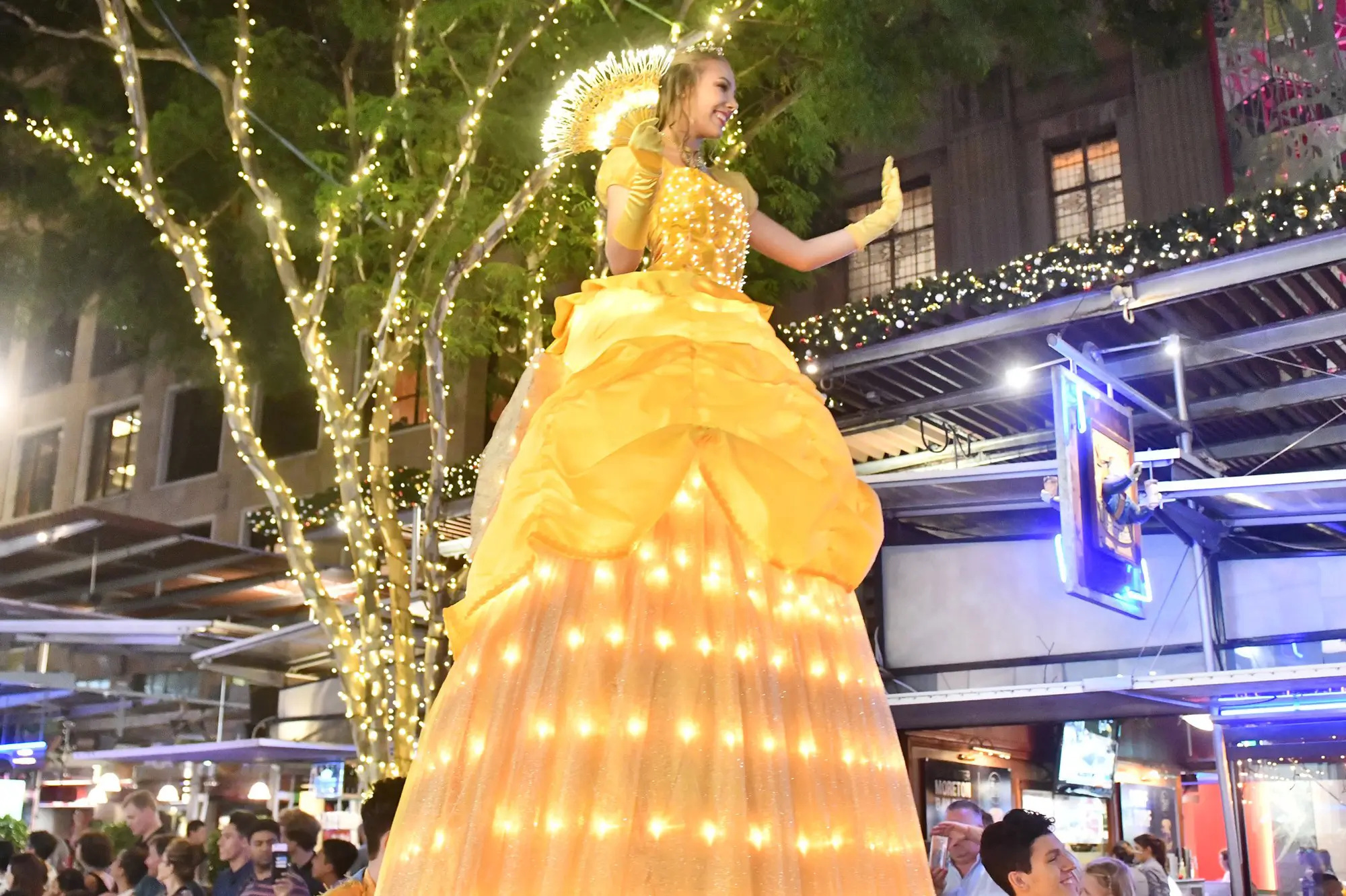 A 3.6 metre tall princess in a yellow dress covered with lights moves through the crowd of Queen Street Mall