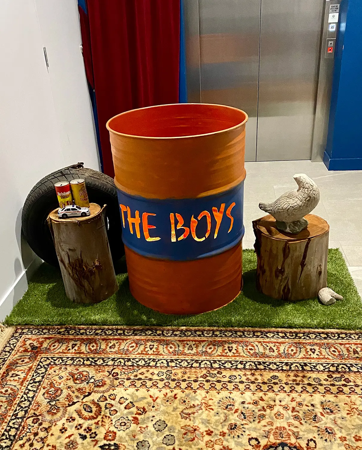 A steel barrel fire pit, an old tire, two tree stumps and other items inside a lobby